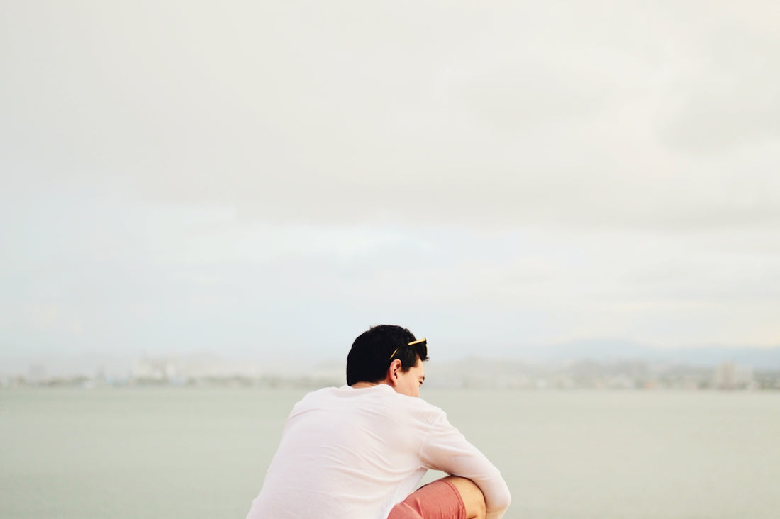 man in white t-shirt sitting on rock