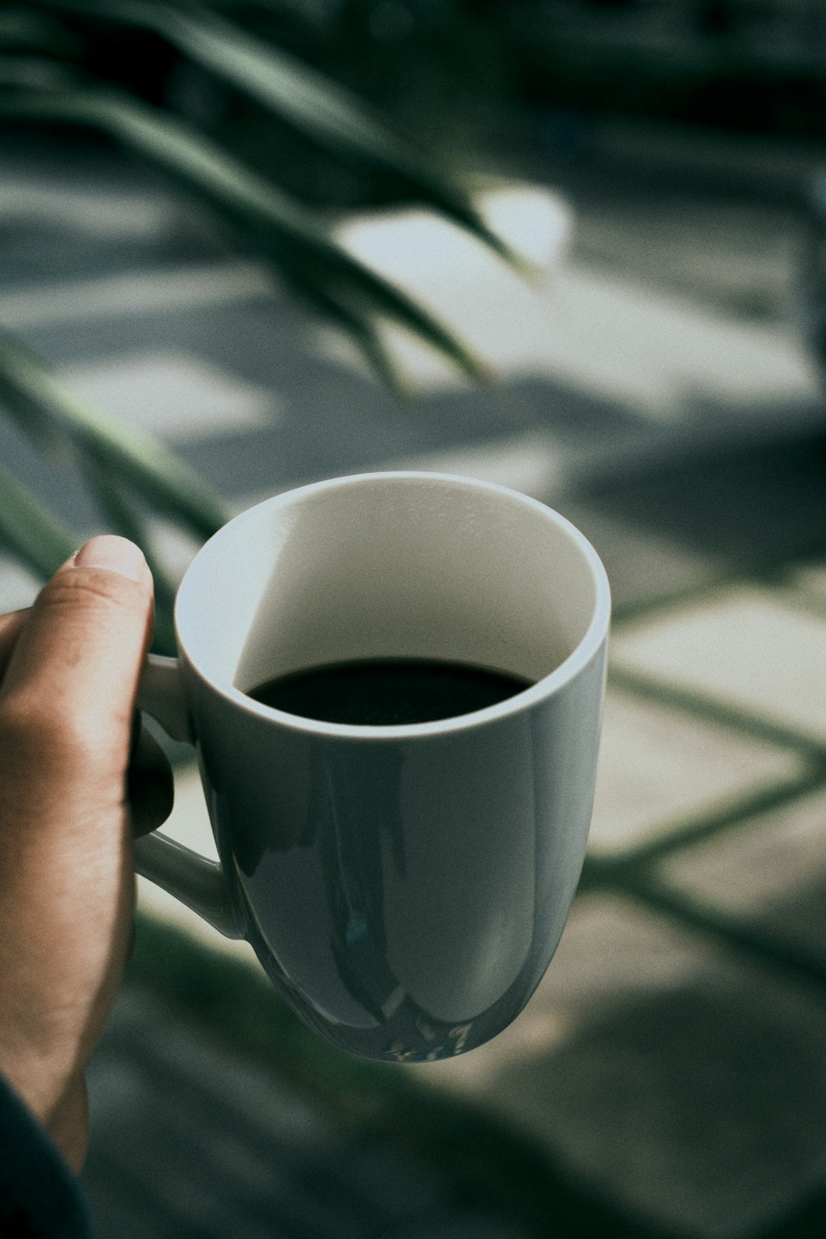 person holding white ceramic mug with black liquid