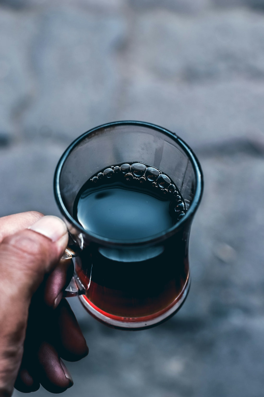 person holding clear glass mug with brown liquid