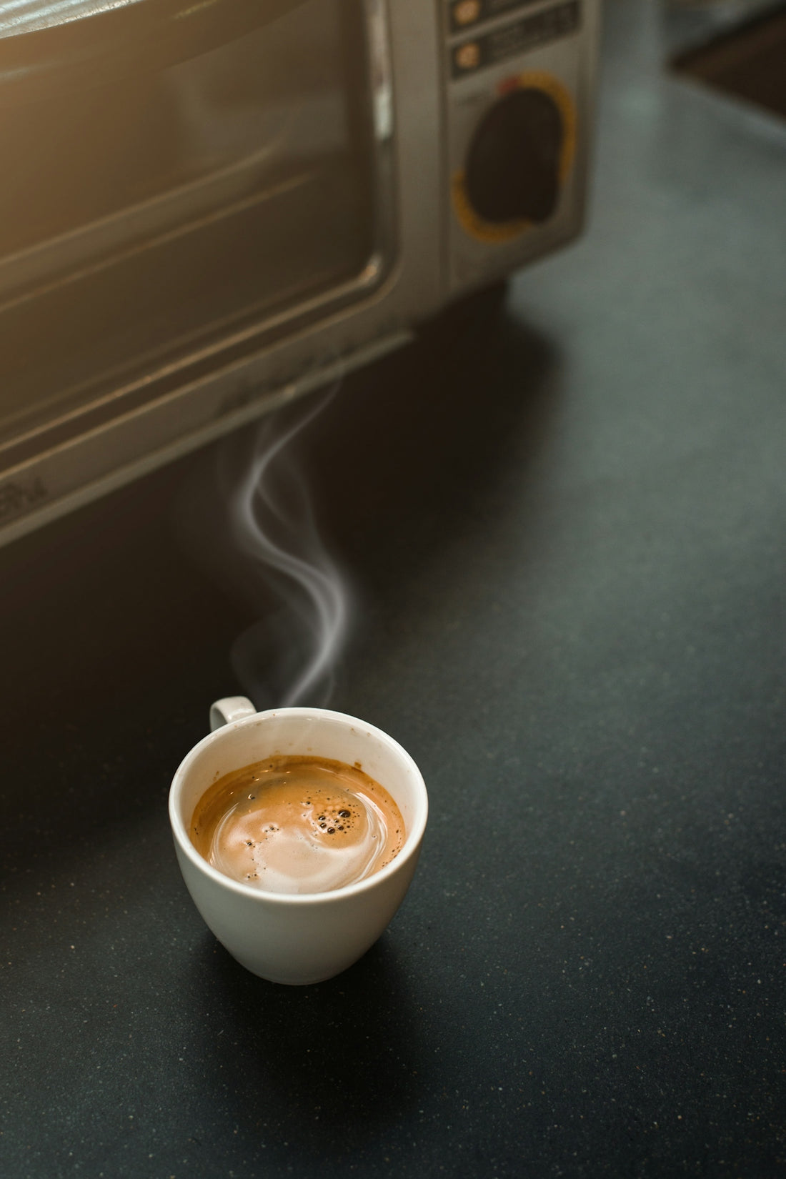 a cup of coffee sitting in front of a toaster oven