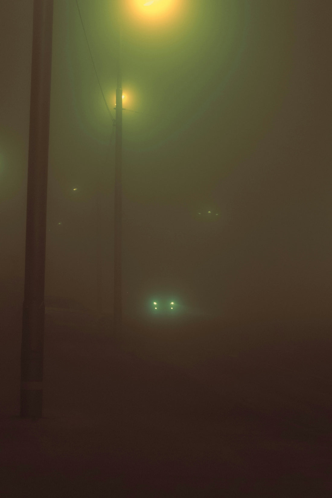 Foggy night with street lights and car headlights.
