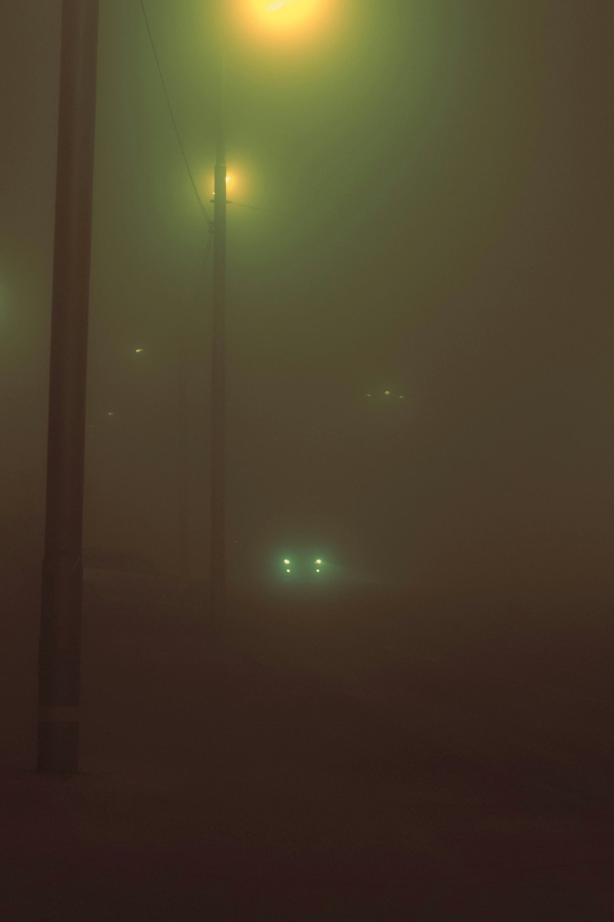 Foggy night with street lights and car headlights.
