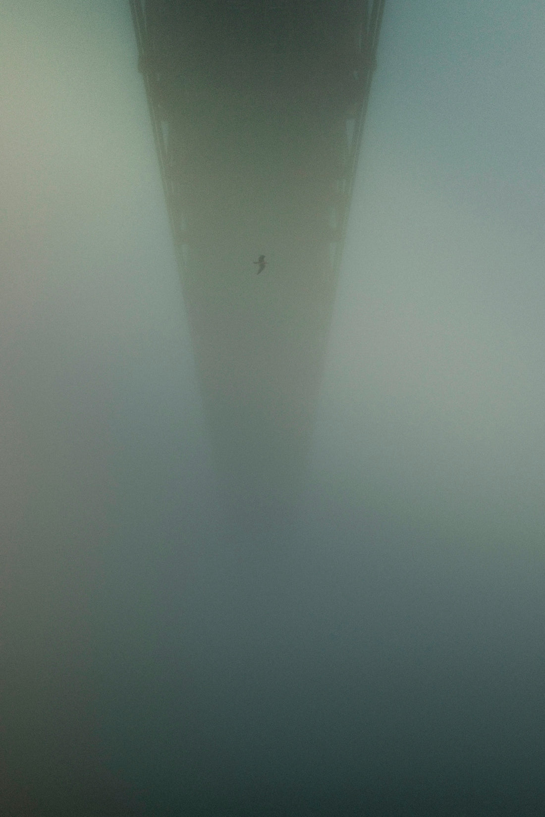 A bridge extends into heavy fog.