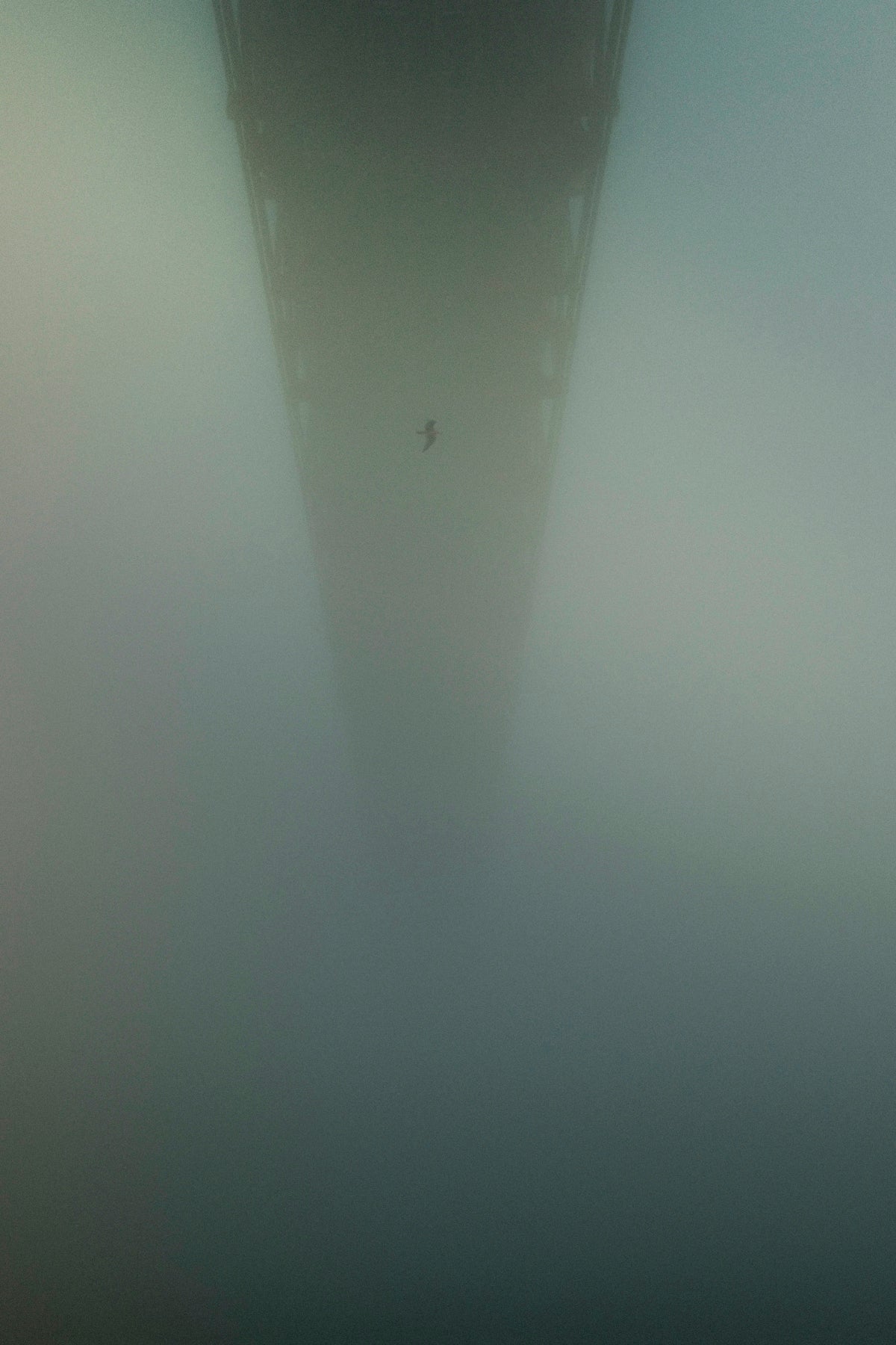 A bridge extends into heavy fog.