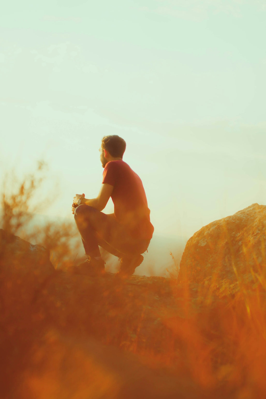 a man sitting on top of a large rock