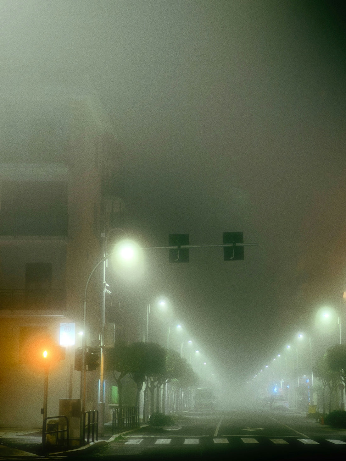 A foggy city street at night with street lights