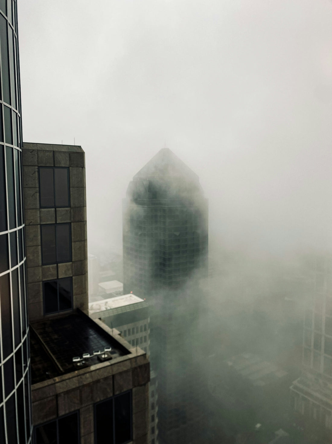 Skyscrapers shrouded in thick fog on an overcast day.