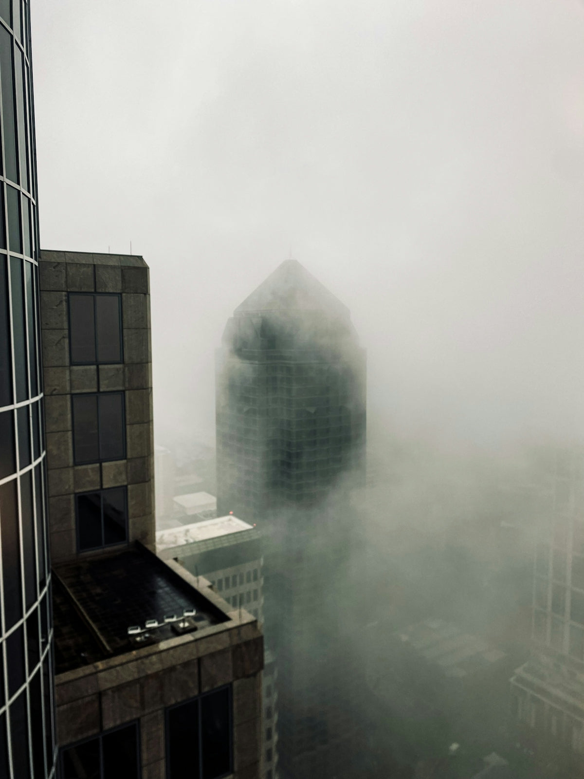 Skyscrapers shrouded in thick fog on an overcast day.